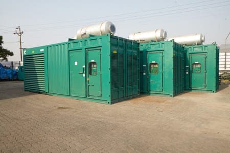 Row of green containerised diesel generator sets with exhaust silencers on the roof